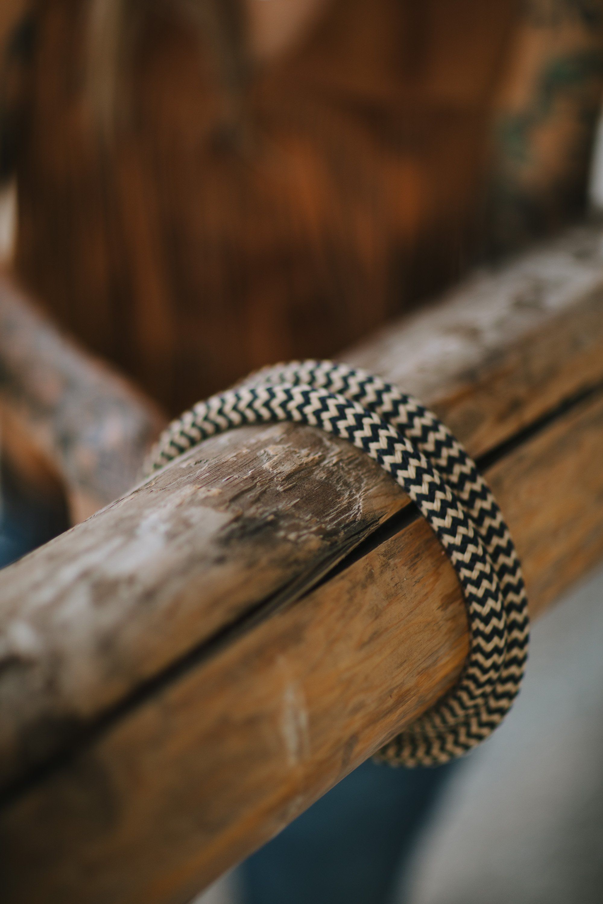 Close-up of a beaded silver bracelet draped over a weathered wooden branch in soft natural light