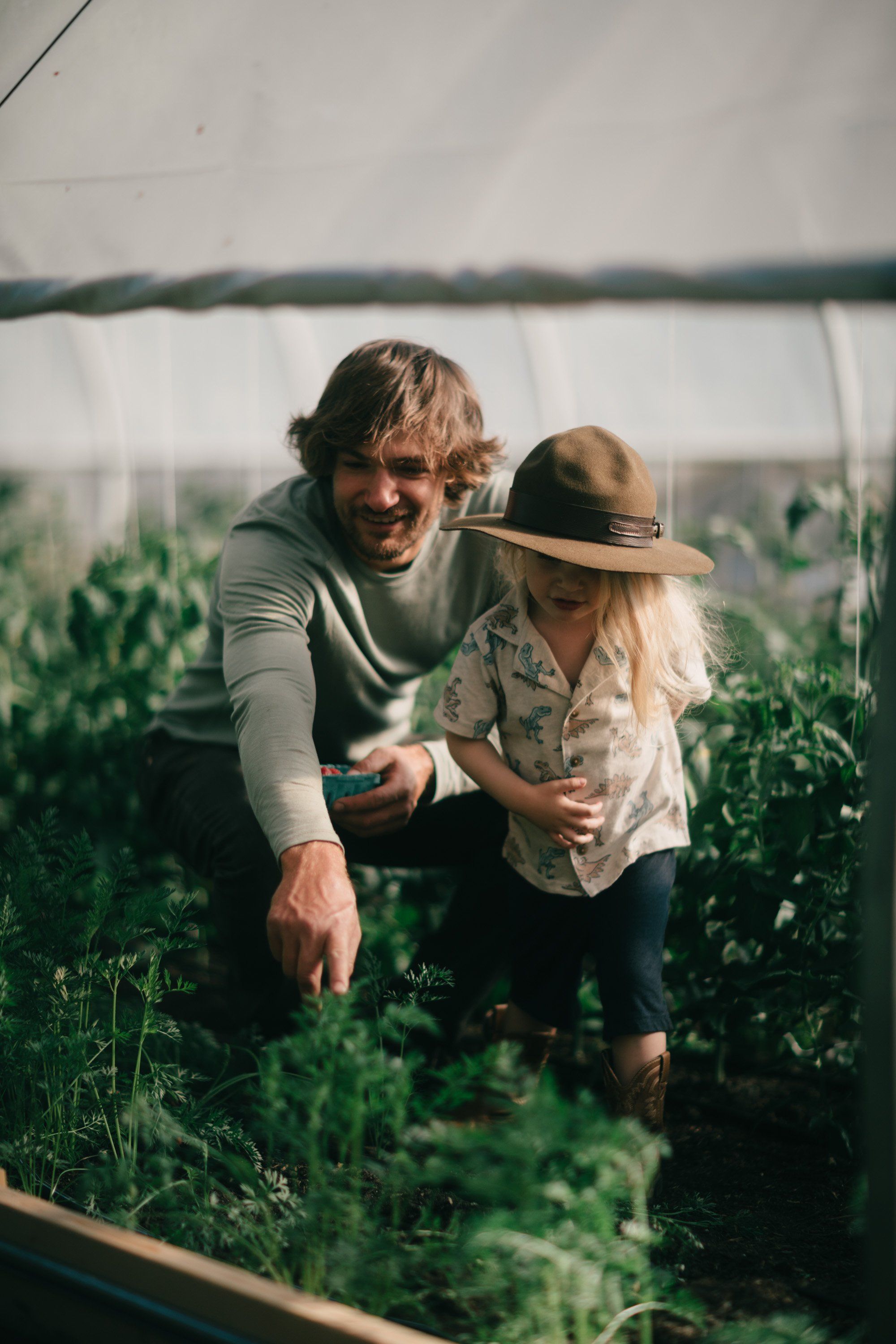 Man and woman examining plants together in a lush greenhouse on Salt Spring Island