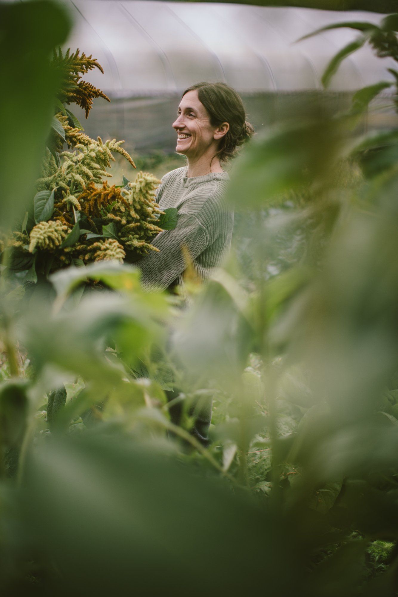 Man smiling among lush garden plants at Bullock Lake Farm, soft natural light filtering through foliage