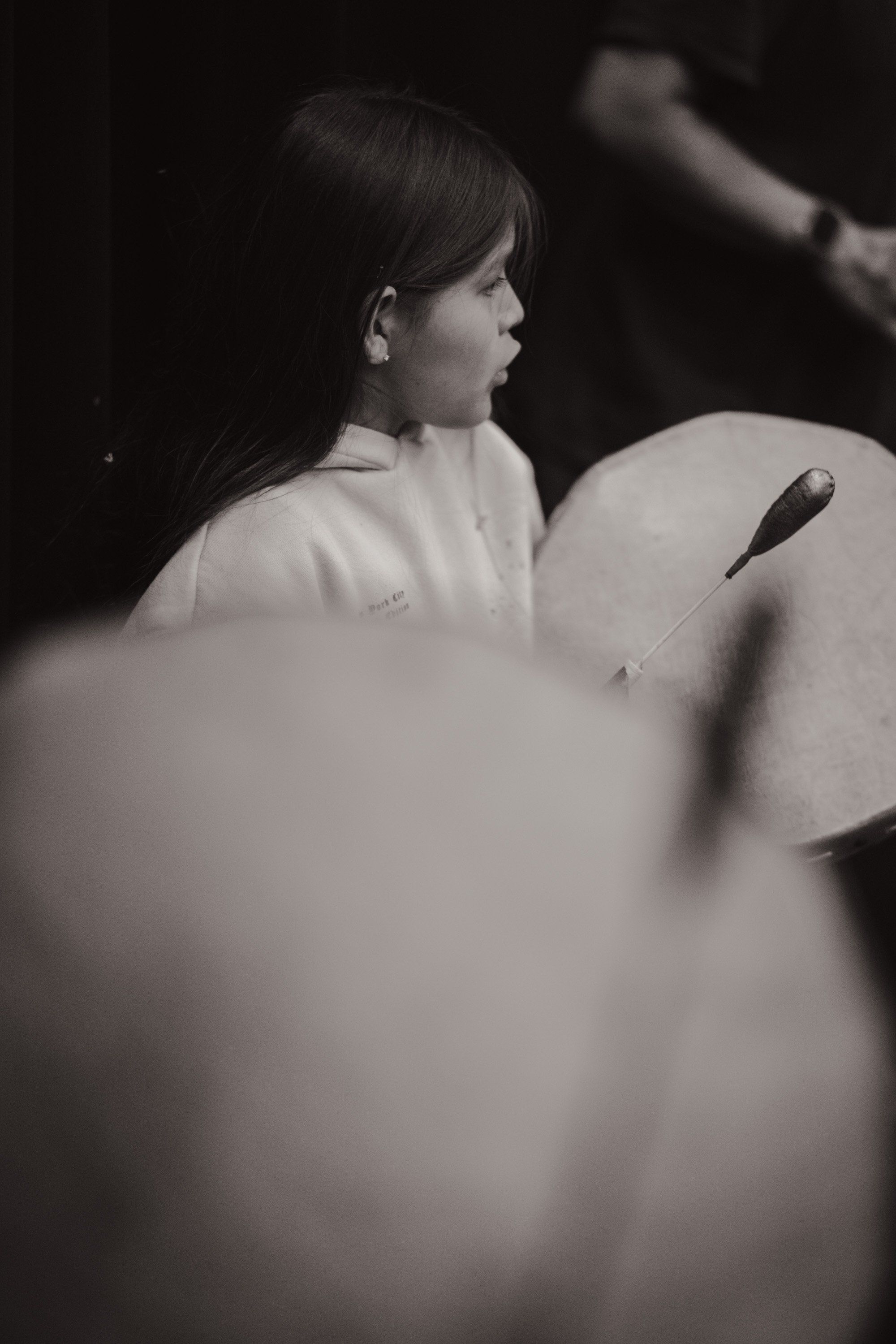 Young child in profile singing, illuminated against softly blurred spherical forms in dramatic black and white light