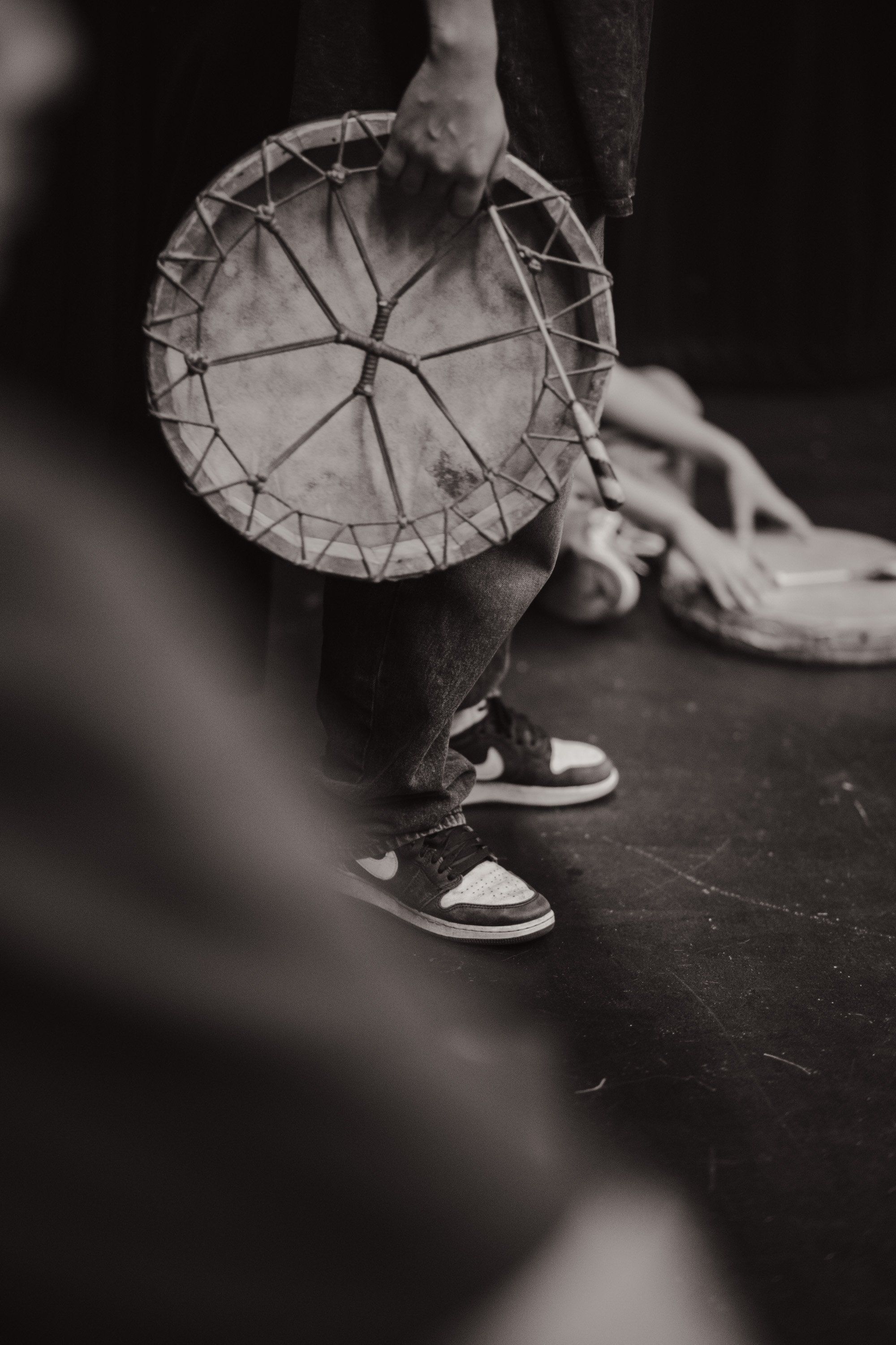 Close-up of hands holding a traditional woven circular basket against dark clothing, captured in black and white