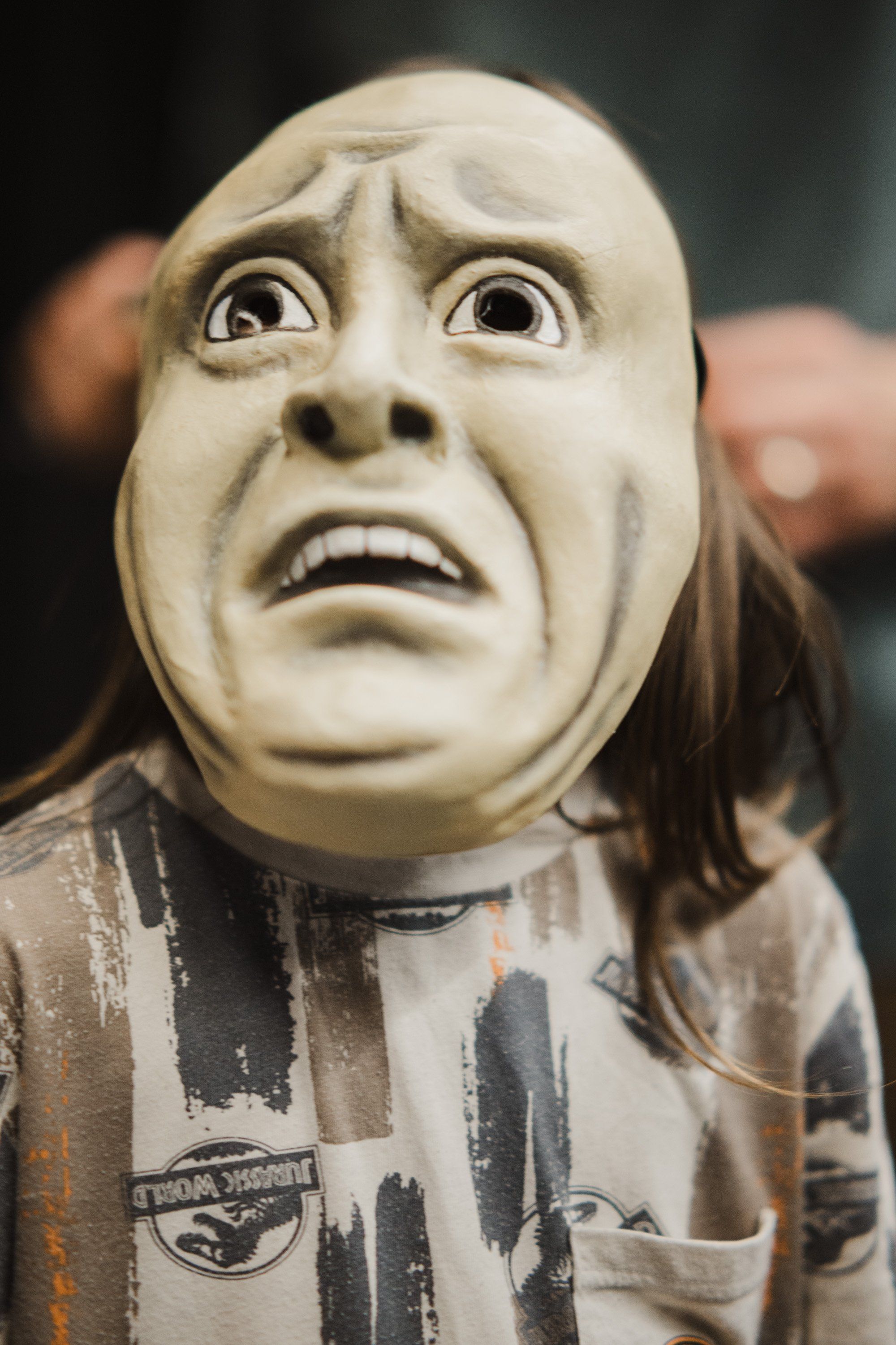 Dancer wearing carved mask with anguished expression and long dark hair, striped regalia visible, captured mid-performance during Coast Salish celebration