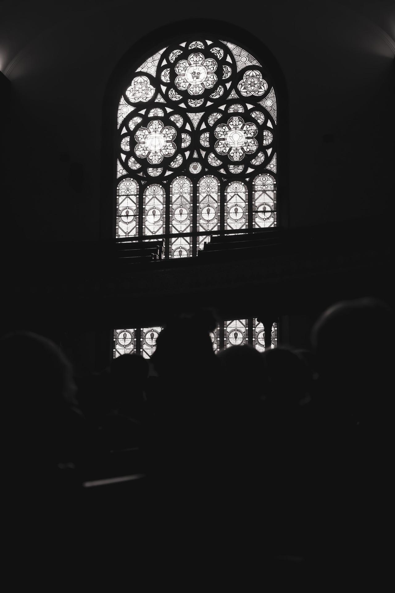 Ornate stained glass windows with geometric and religious motifs against dark stone tracery in a Gothic cathedral