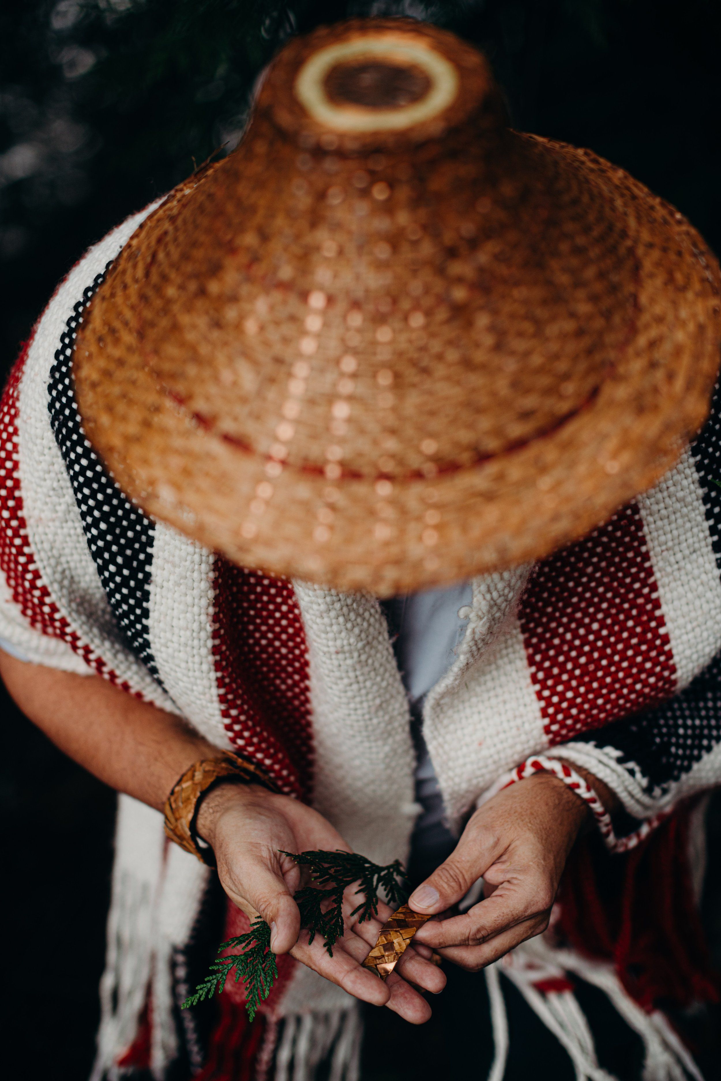 Hands holding dried plants against striped textile and woven hat in natural light portrait