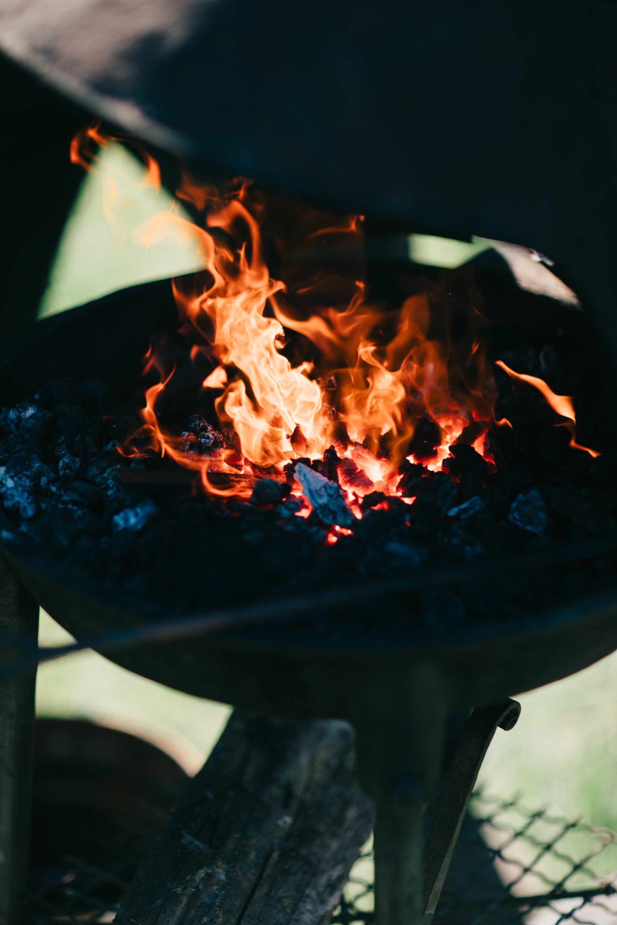 Flames leap from a metal fire bowl as cream-colored fabric drapes catch the golden light against a dark background