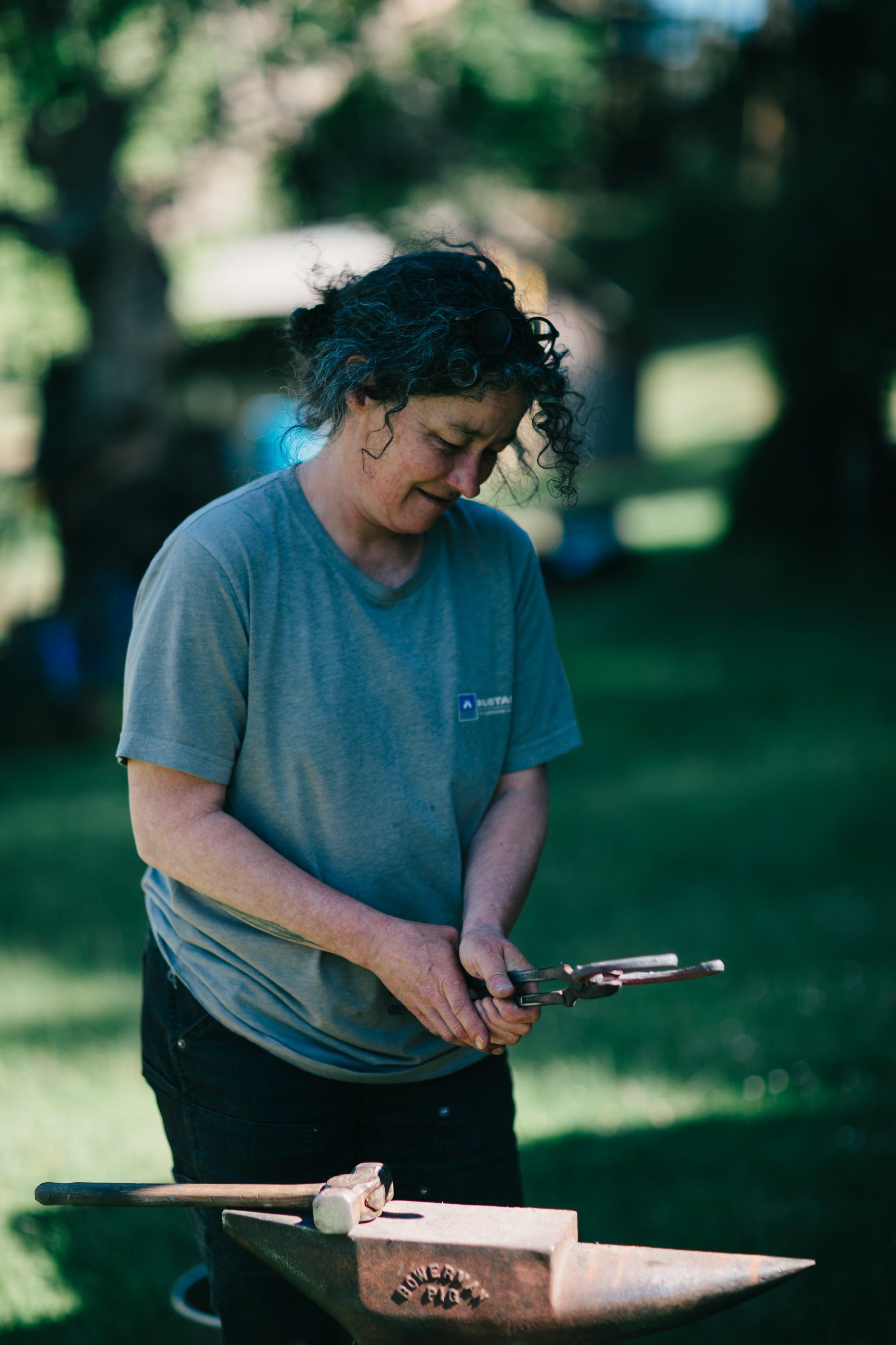 Person carving wood with a chisel at a rustic workbench on a sunlit farm, focused on their craft