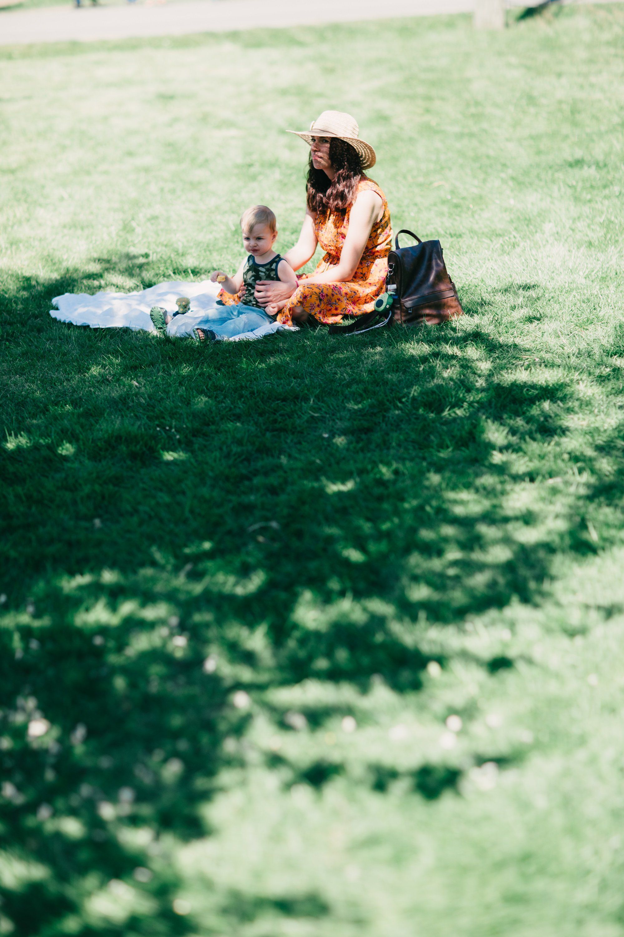 Woman and child sitting on white blanket in dappled shade under trees on green grass at Ruckle Farm