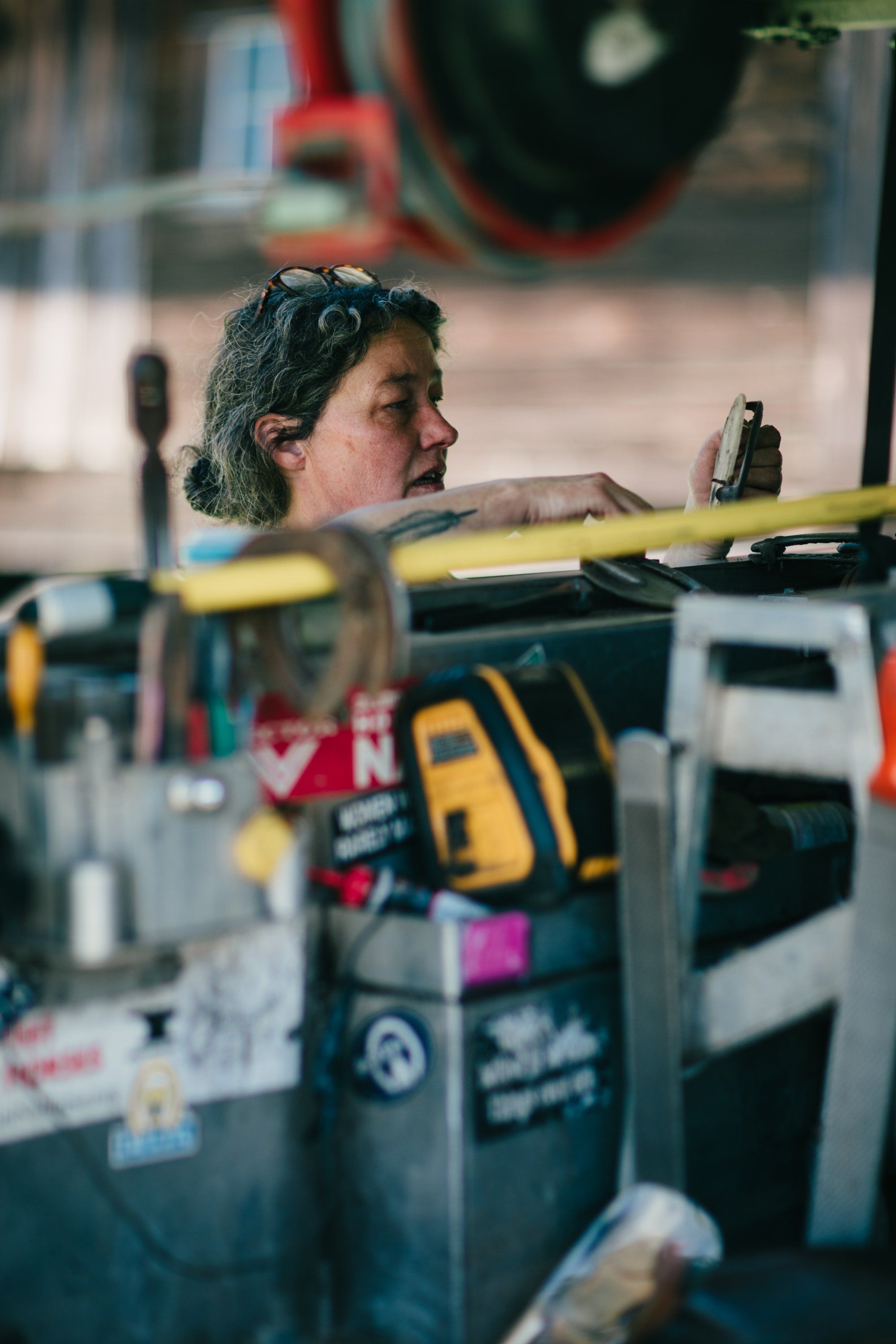 Person in profile examining farming equipment with tools and machinery visible in soft natural light at Ruckle Farm