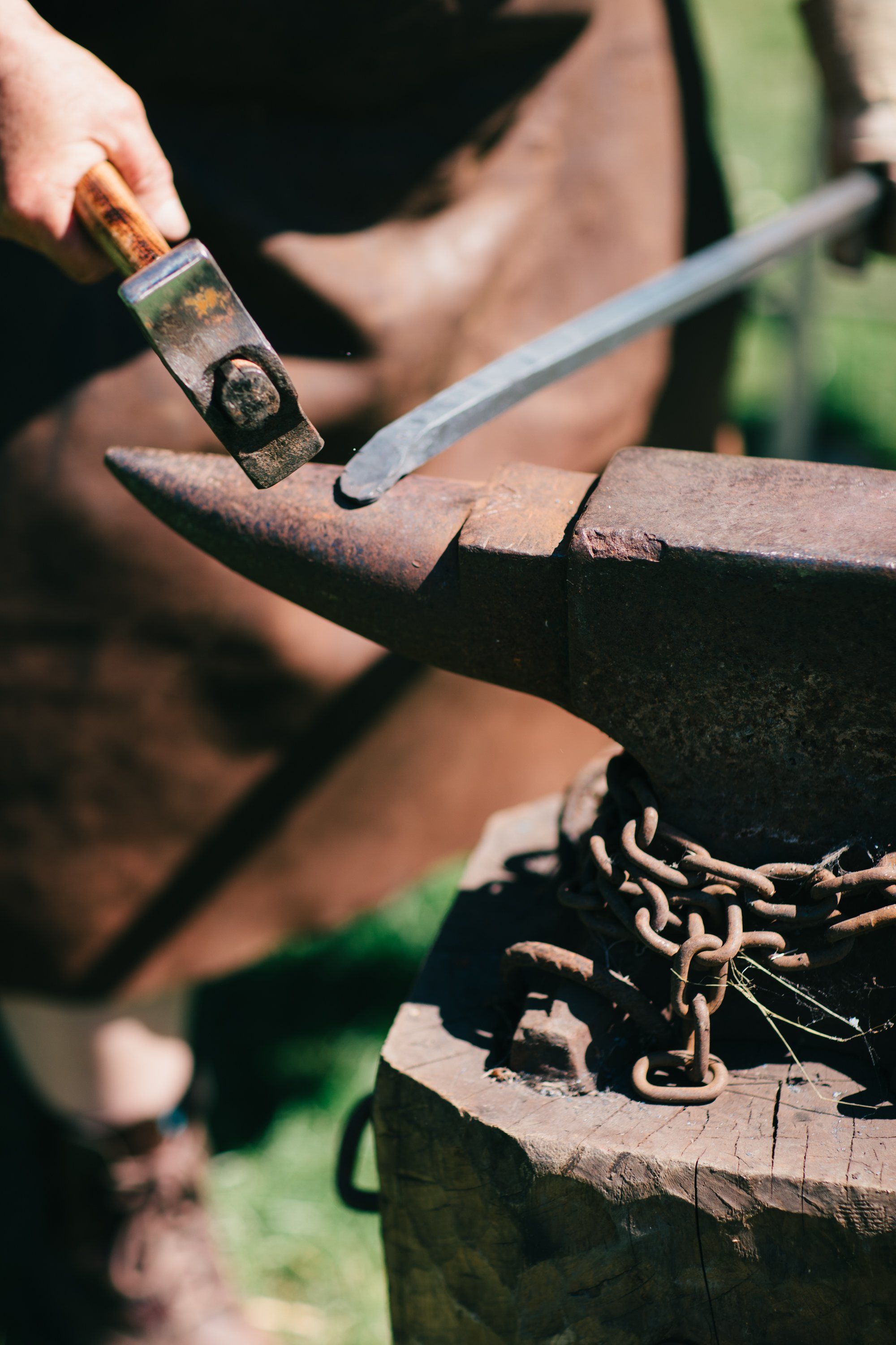 Weathered hands apply wood stain to a rustic farm implement in golden afternoon light