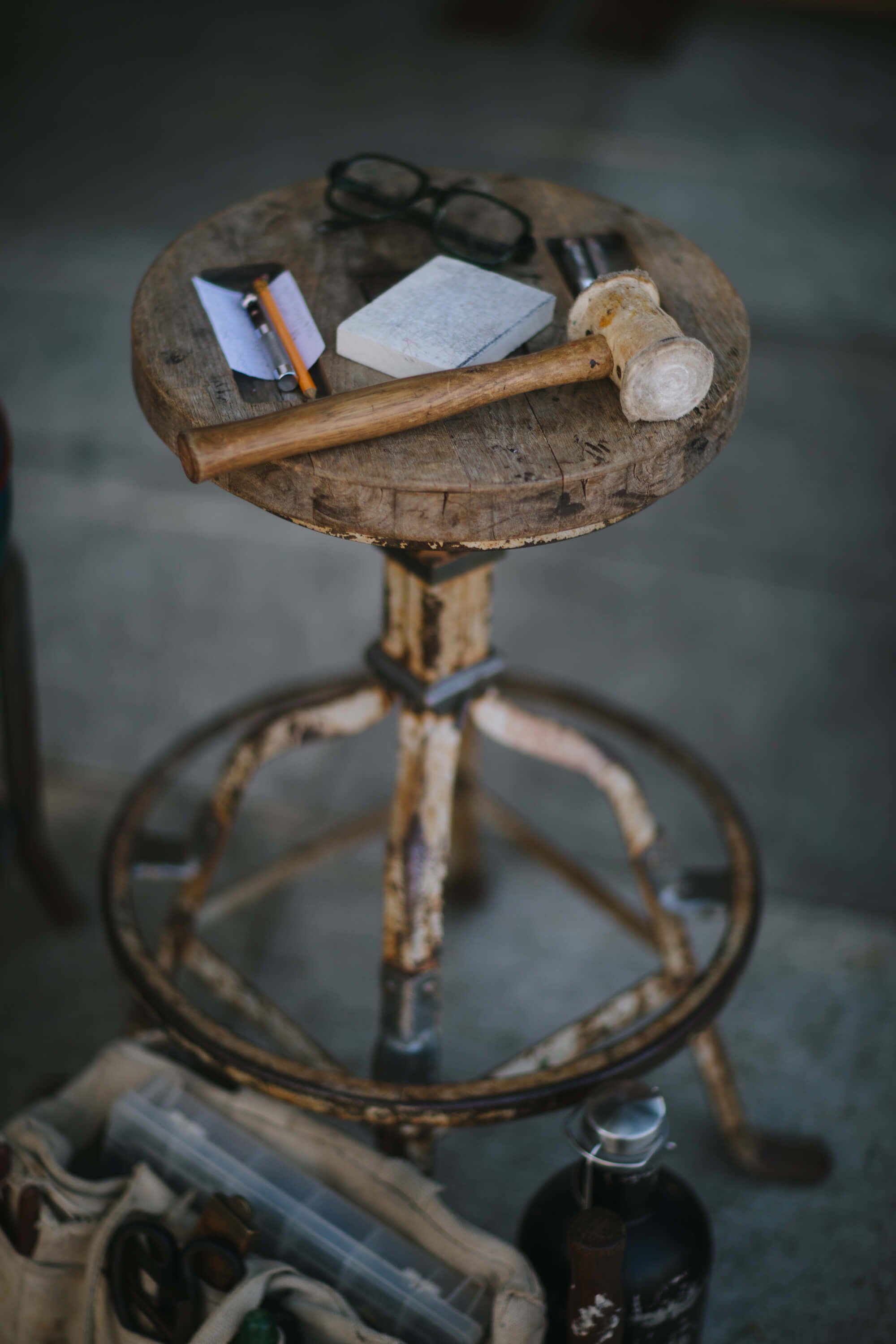 Weathered vintage bicycle seat table displaying eyeglasses, notebook, and found objects at a rustic market stall