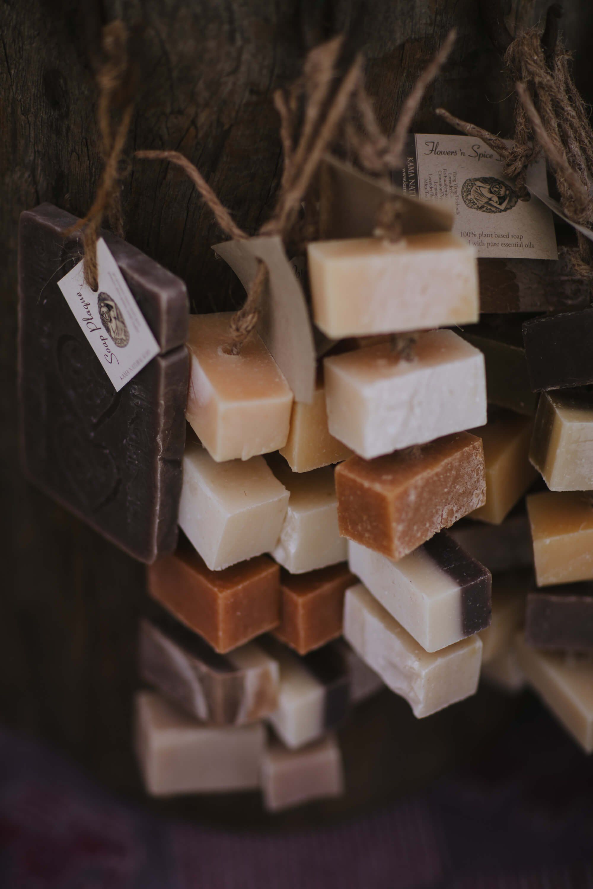 Handmade soaps stacked and displayed against weathered wood with product tags, warm natural light casting soft shadows