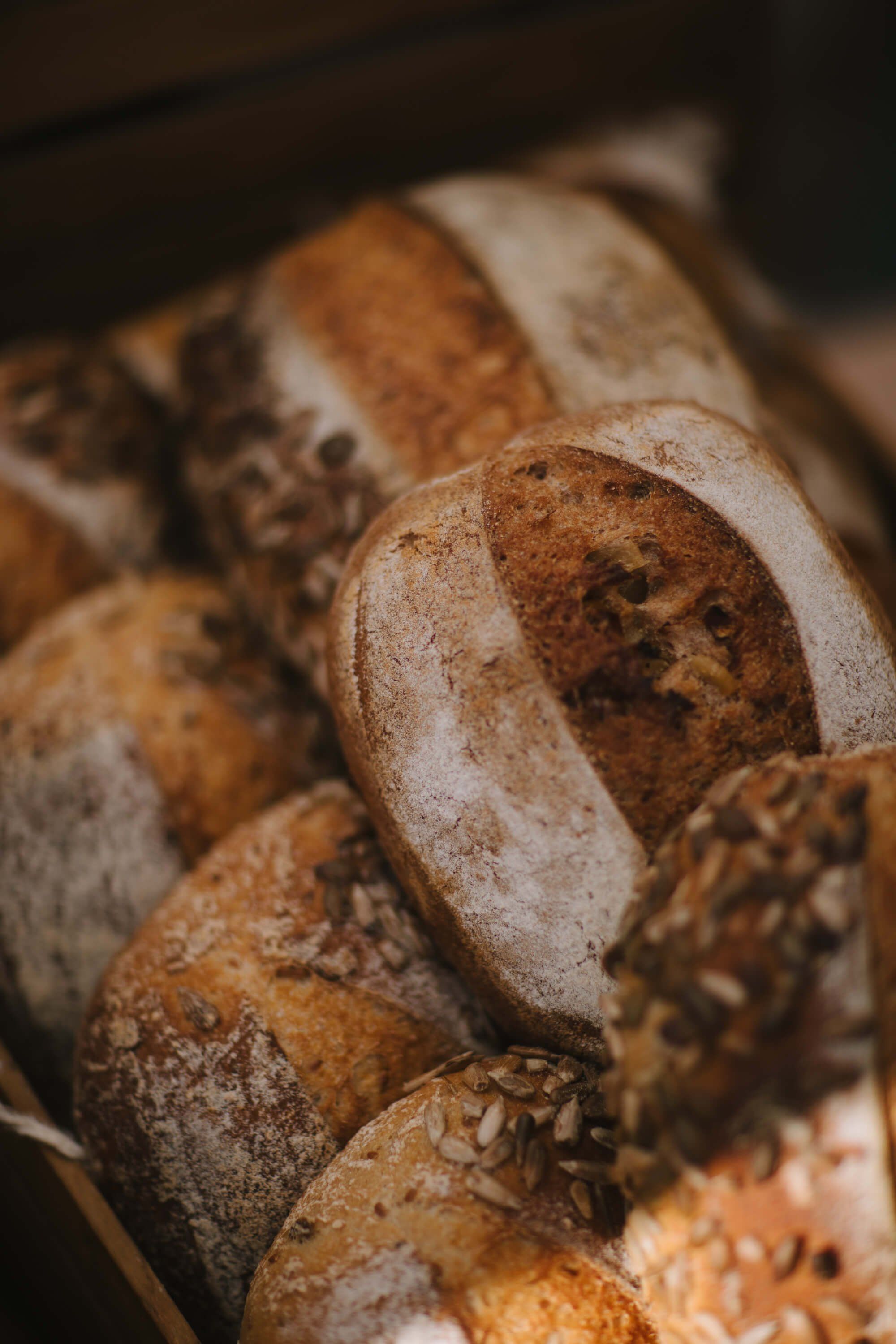 Freshly baked artisan breads with crusty exteriors and flour dusting arranged in warm, golden light at the market