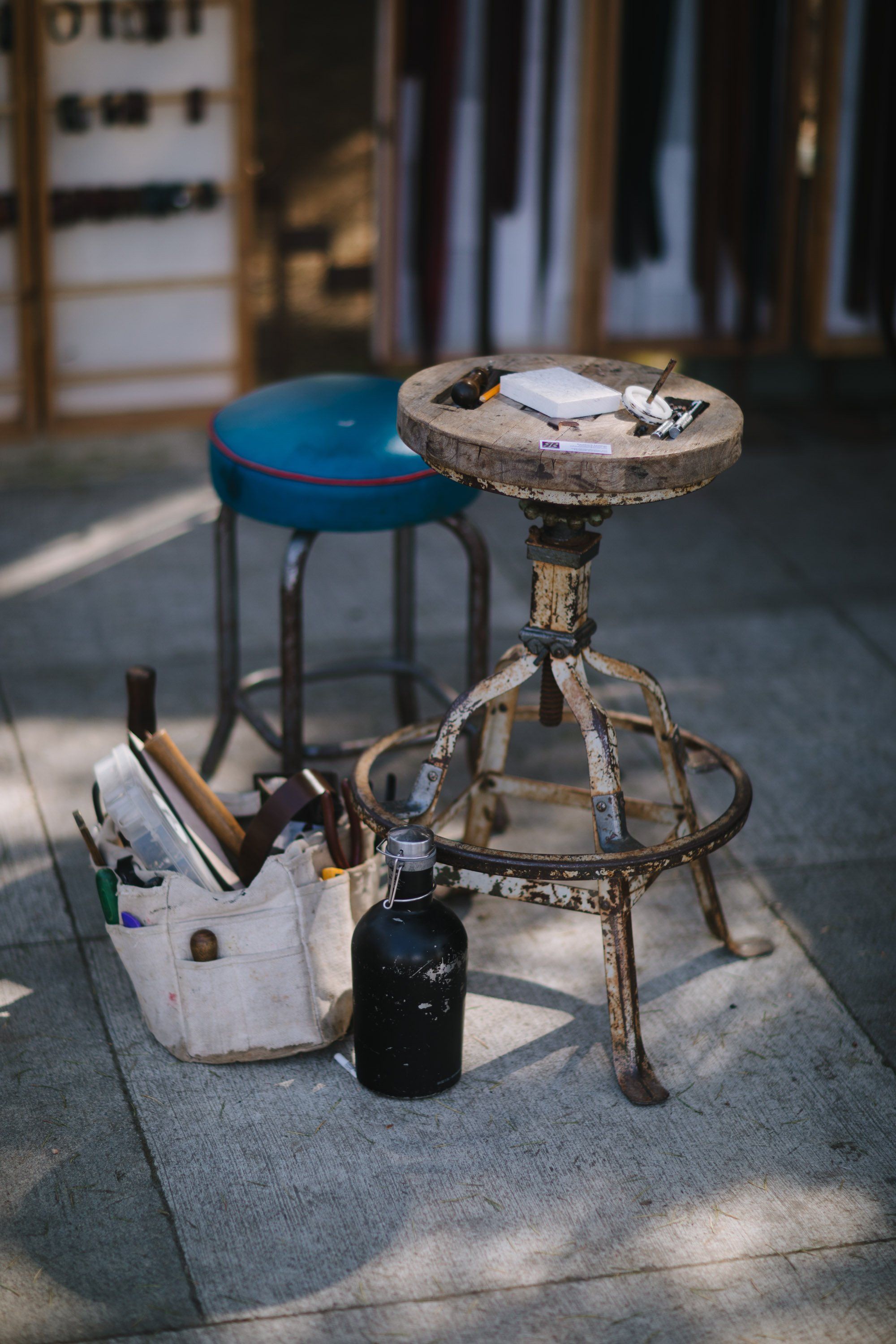 Weathered artist's stool with scattered paintbrushes and supplies in warm sunlight at an outdoor market
