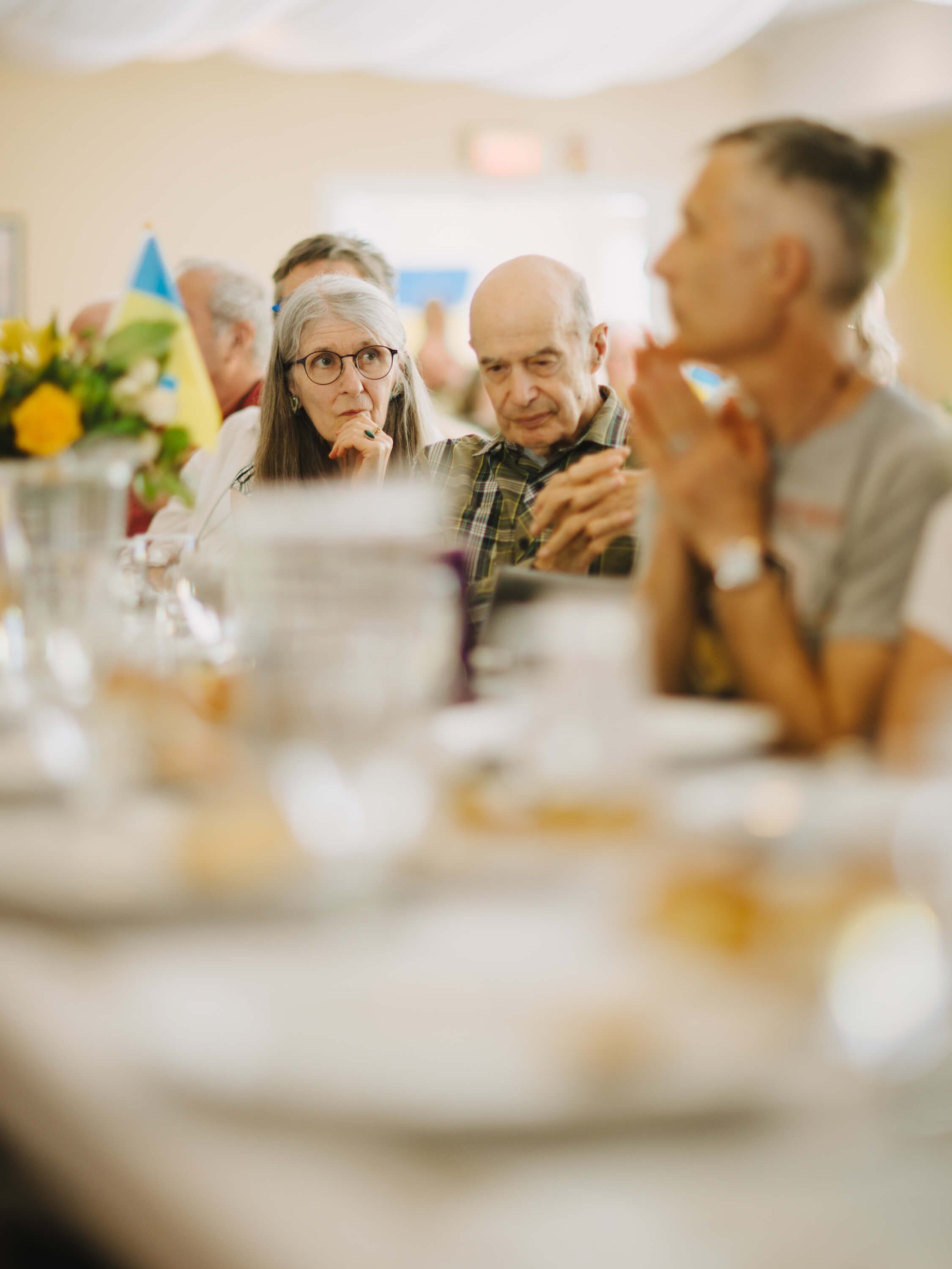 Guests gathered around a candlelit dinner table share conversation and laughter at the Ukrainian fundraiser event