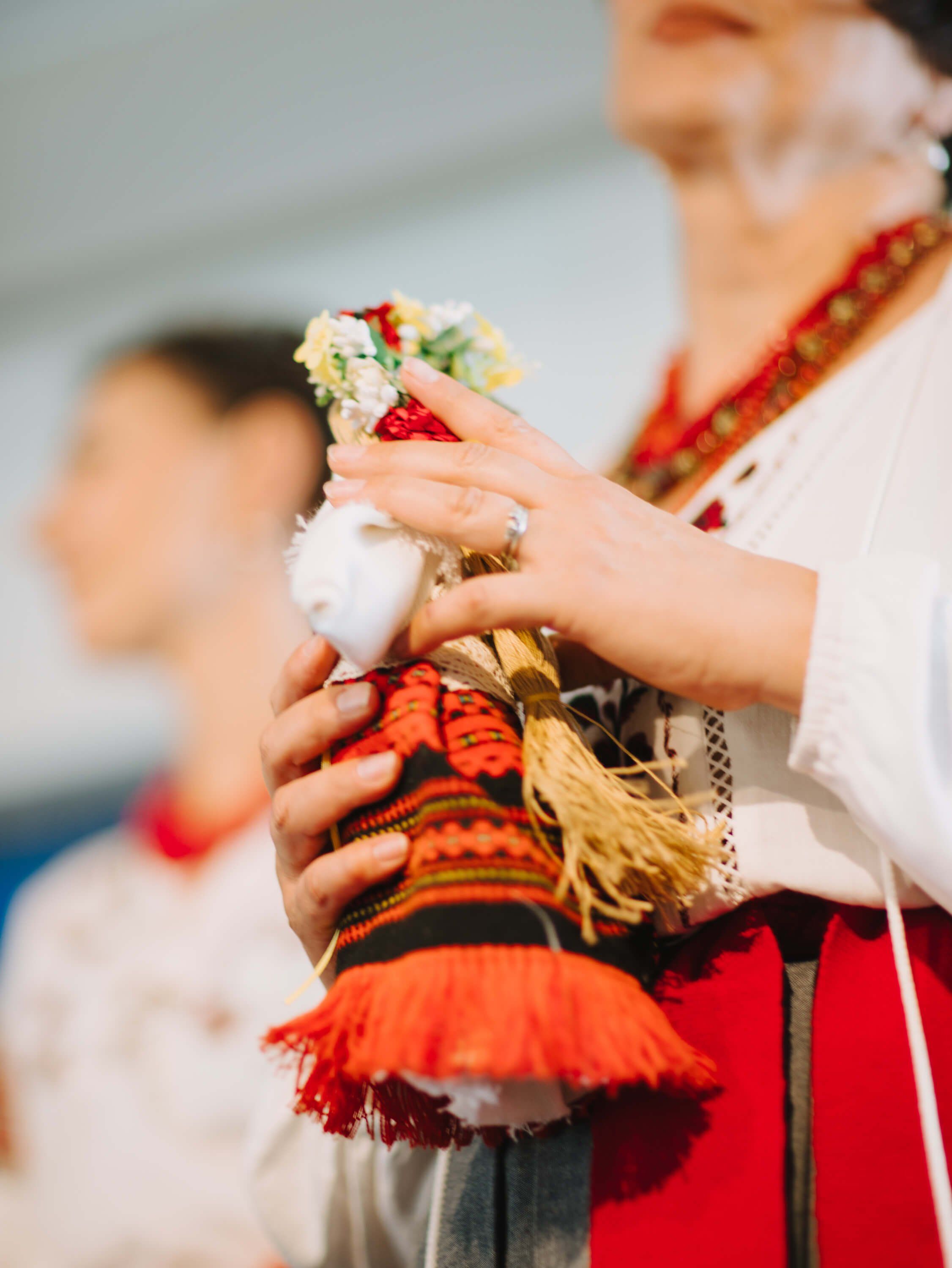 Close-up of hands holding traditional Ukrainian bread and embroidered textile, warm golden light highlighting cultural details