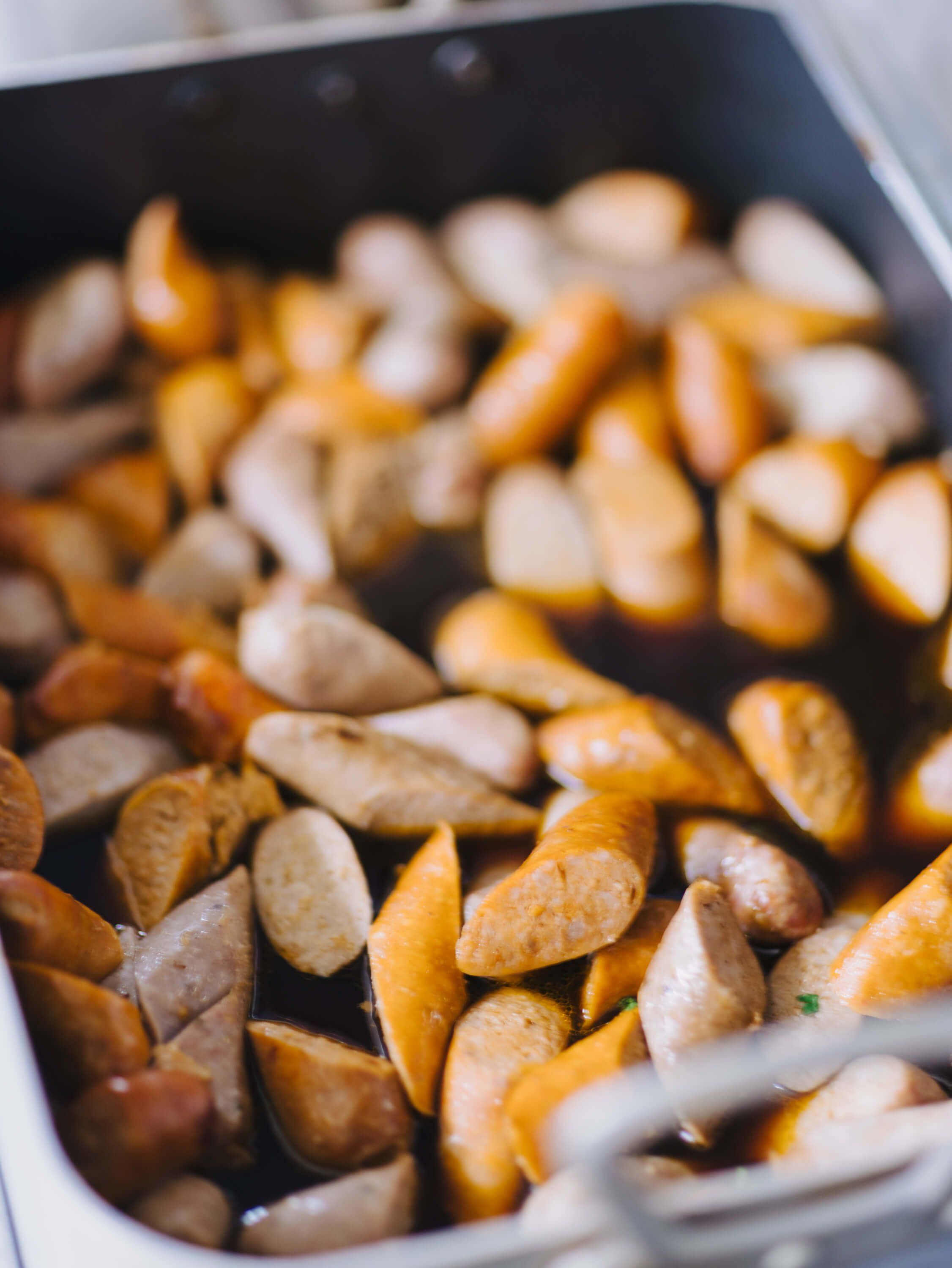 Roasted potatoes and mushrooms in a dark baking dish, golden-brown and glistening under warm light at a Ukrainian fundraiser dinner