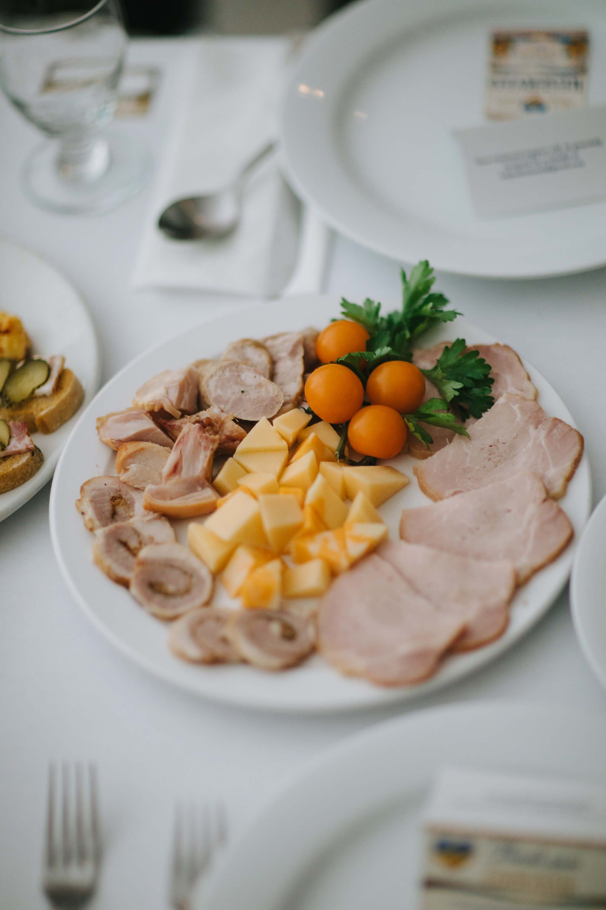 Elegant charcuterie plate with sliced meats, cheese, and apricots arranged on white dinnerware at a formal fundraiser dinner