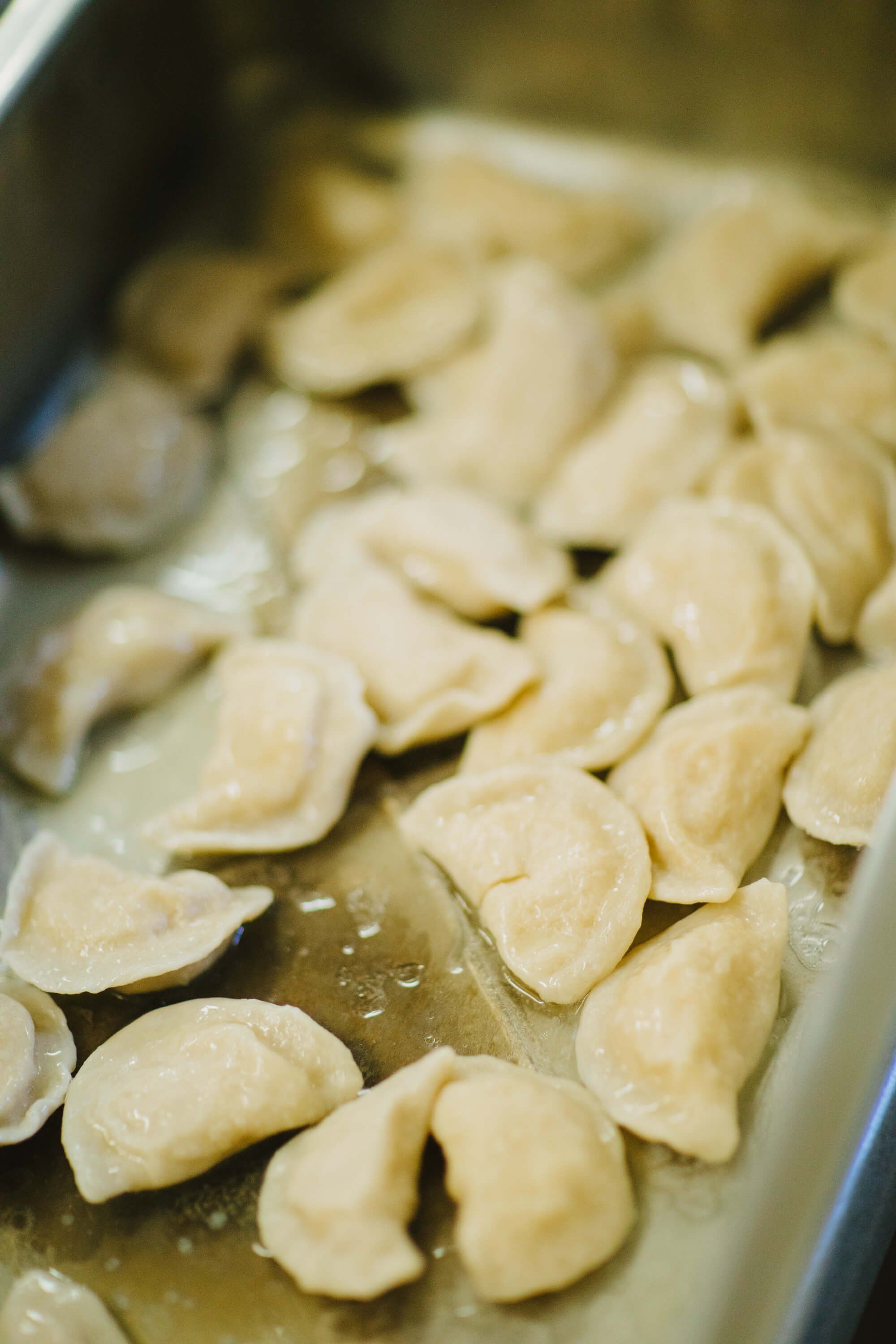 Freshly cooked dumplings float in steaming broth in a shallow bowl, their delicate pleated edges catching warm light