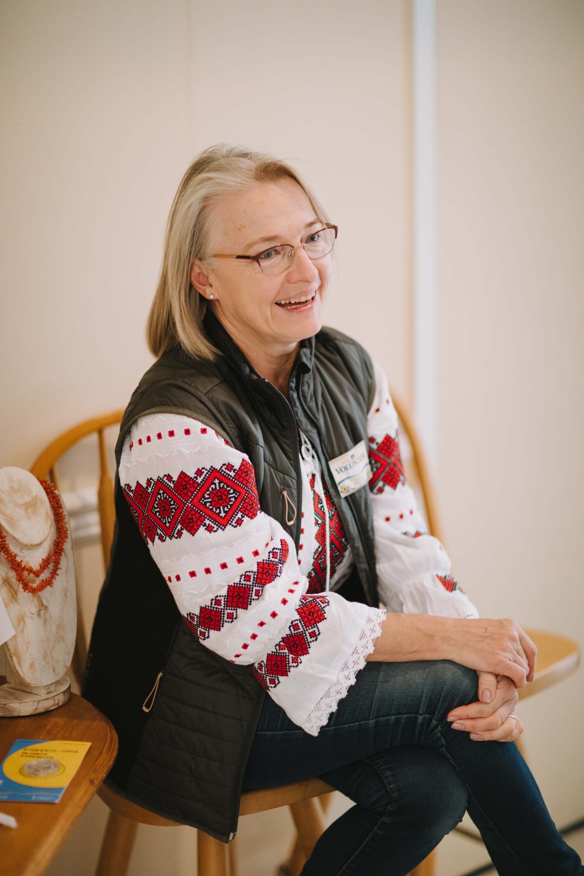 Woman in red and white patterned sweater smiles while seated at a Ukrainian fundraiser dinner event