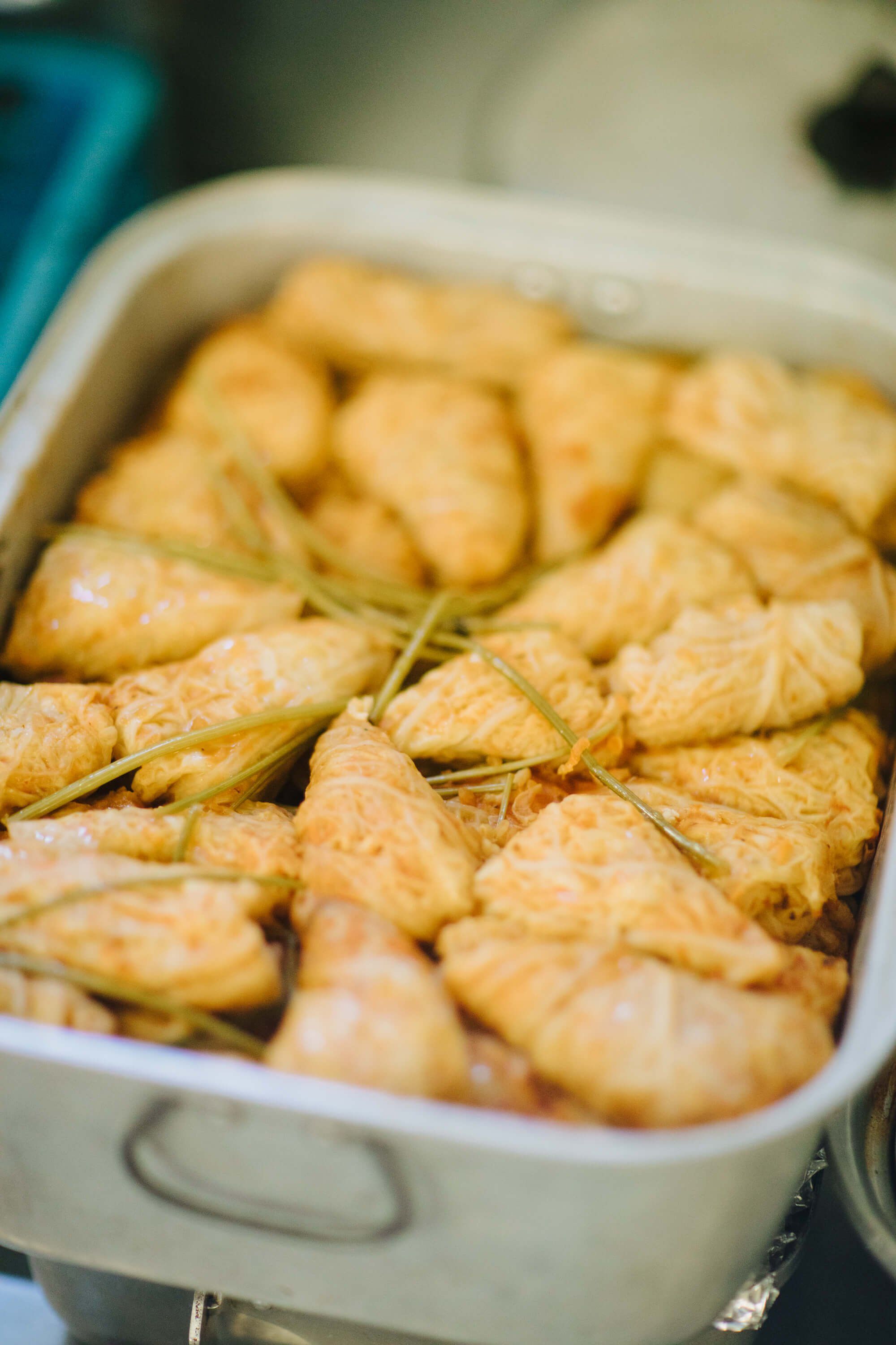 Golden-brown triangle pastries garnished with fresh rosemary sprigs arranged in a white ceramic dish at the Ukrainian fundraiser dinner
