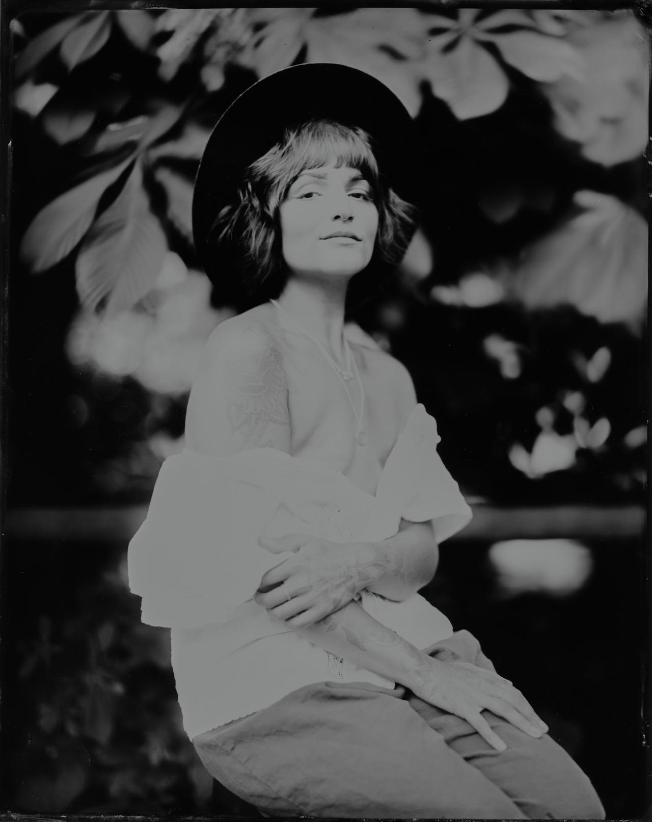 Person in wide-brimmed hat gazing upward with contemplative expression, black and white portrait