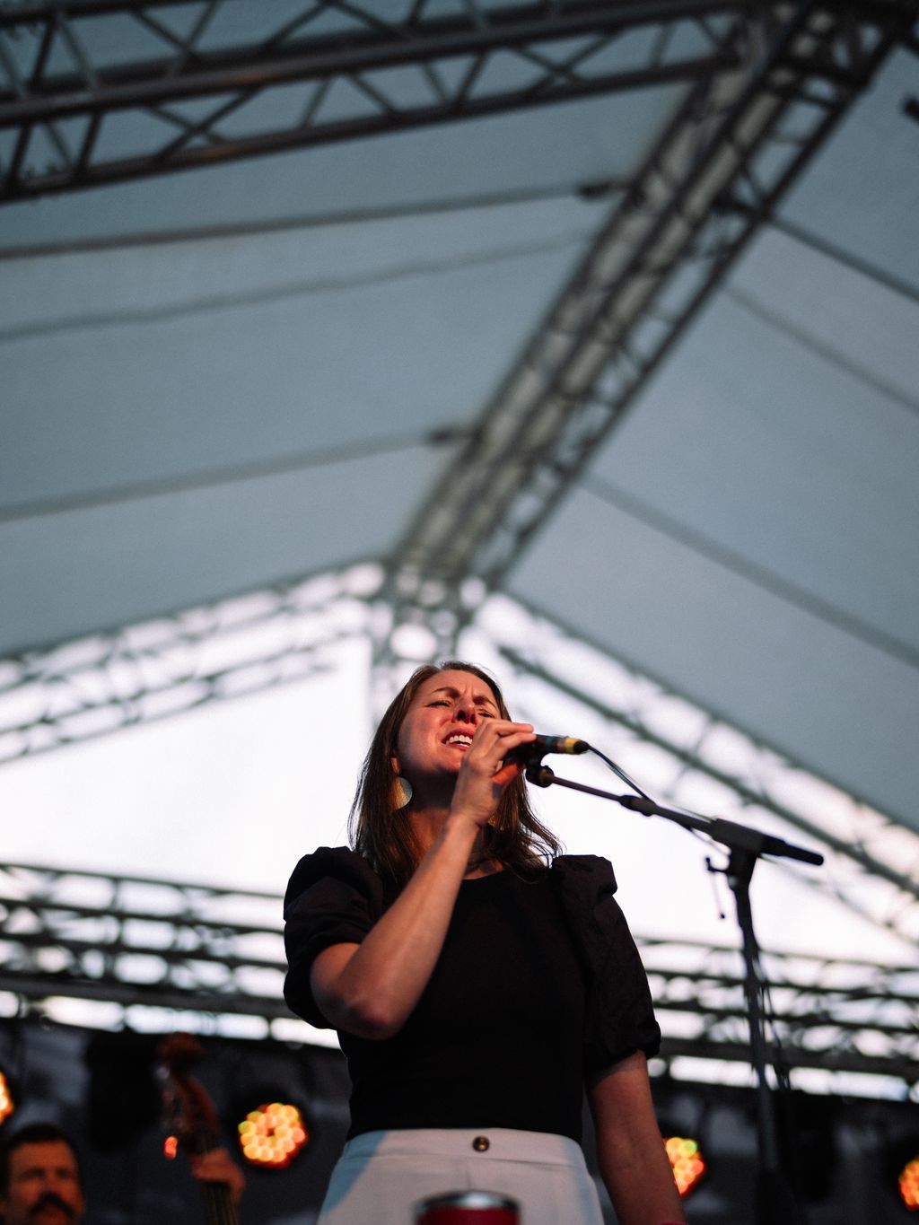 Singer performs at microphone under industrial ceiling at Pitchfork Social event
